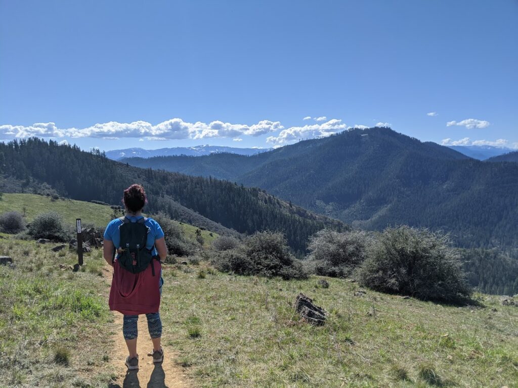 Woman looking at mountain views on a hiking trail.
