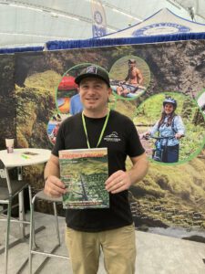 Individual standing in front of a background holding a visitor guide