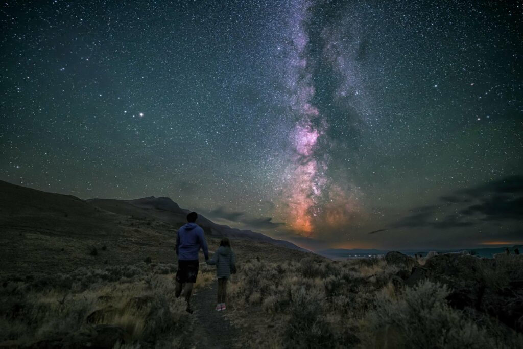 Father and daughter looking at milky way